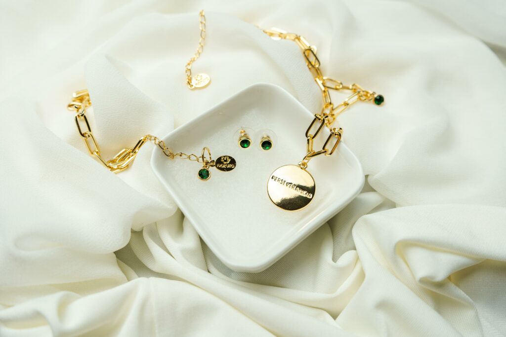 Luxurious gold jewelry set with emerald stones elegantly displayed on white fabric, perfect for bridal accessories.